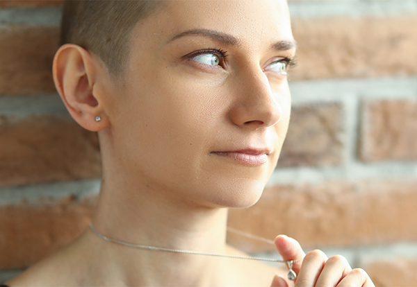 woman-with-creative-hairstyle-looking-out-window-standing-near-brick-wall-600w Pensive woman seeking therapy