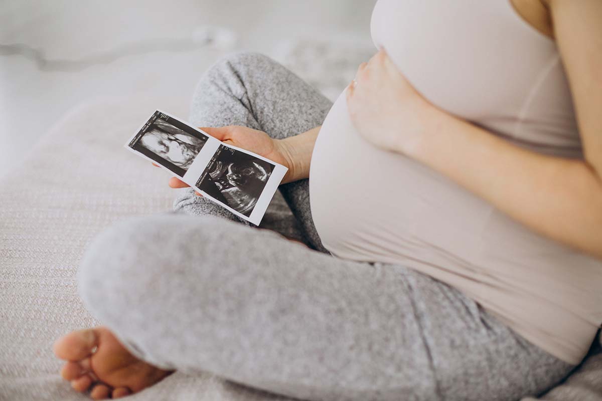 pregnant-woman-with-ultrasound-photo-sitting-bed